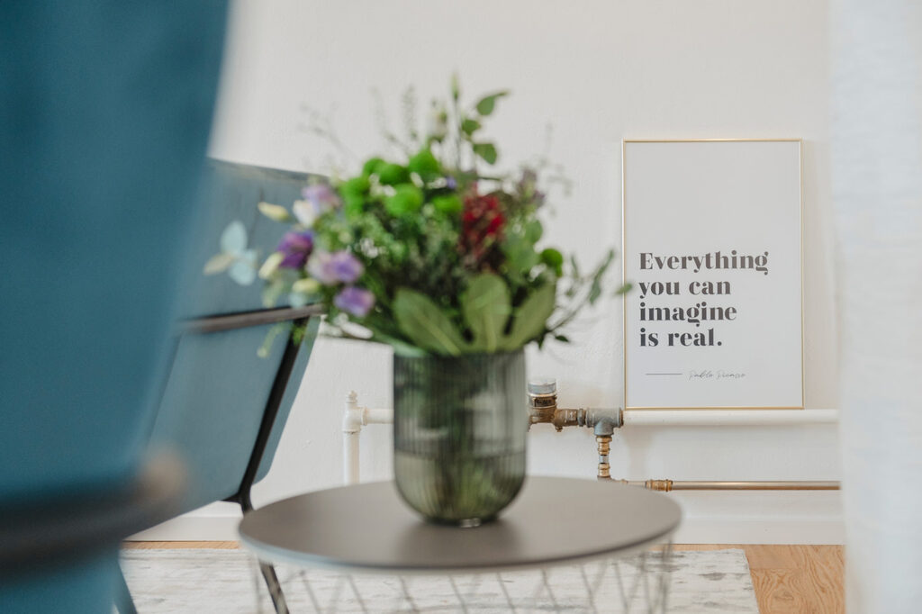 www.felixbaabphotography.de Blumenstrauß auf einem Beistelltisch, dahinter ein gerahmtes Bild mit dem Satz »Everything you can imagine is real«