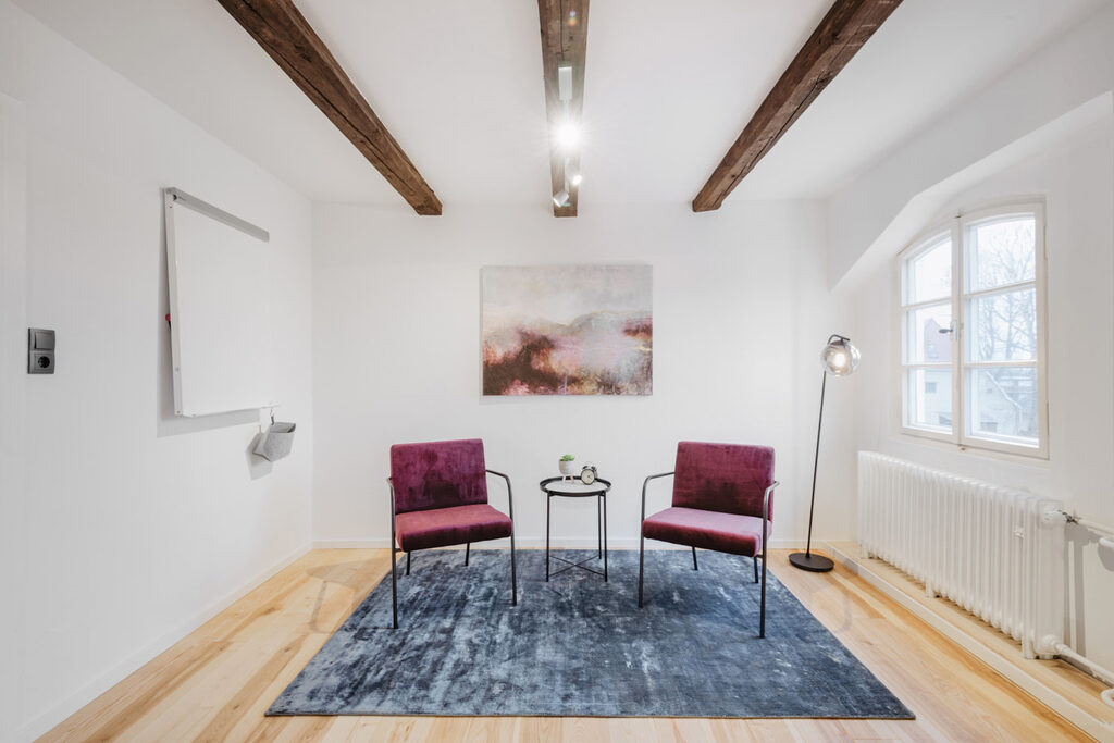 www.felixbaabphotography.de Kleiner Coachingraum mit zwei roten Sesseln, Beistelltisch und Whiteboard