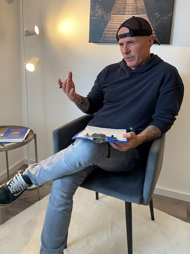 Sepp Kraus web 2 Sepp Kraus sitzt im Sessel und spricht, ein Klemmbrett auf dem Knie